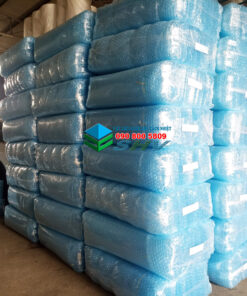 Trong kho chứa nhiều cuộn vật liệu cách nhiệt màu xanh dương, được đóng gói trong túi nilon và xếp chồng lên nhau.