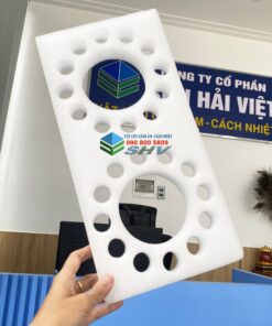 Tấm xốp trắng có lỗ, vật liệu cách âm cách nhiệt, được cầm trong văn phòng.