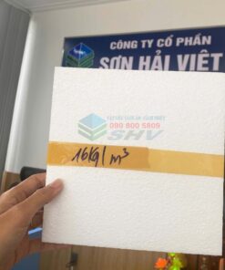 Tấm xốp trắng của công ty Sơn Hải Việt, có ghi thông số 16kg/m³, được cầm trong tay trước bảng hiệu công ty.
