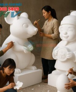 Bốn người đang chạm khắc các tượng foam trắng lớn trong xưởng, có logo và số điện thoại của công ty SHV.